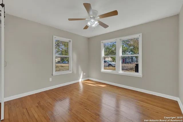 a view of an empty room with wooden floor and a window