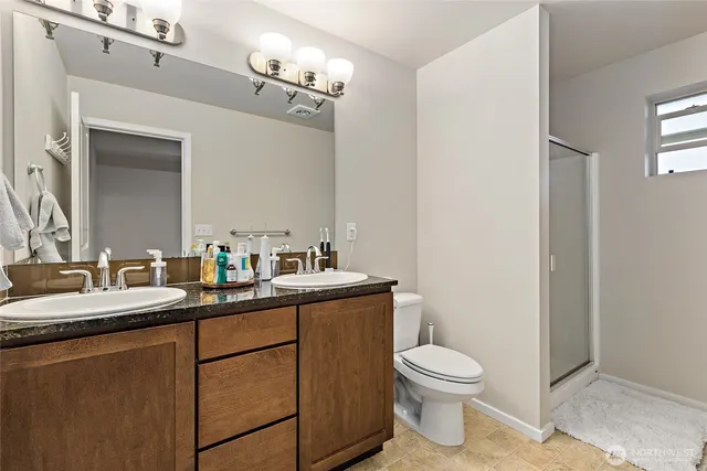 a bathroom with a granite countertop toilet a sink and a mirror