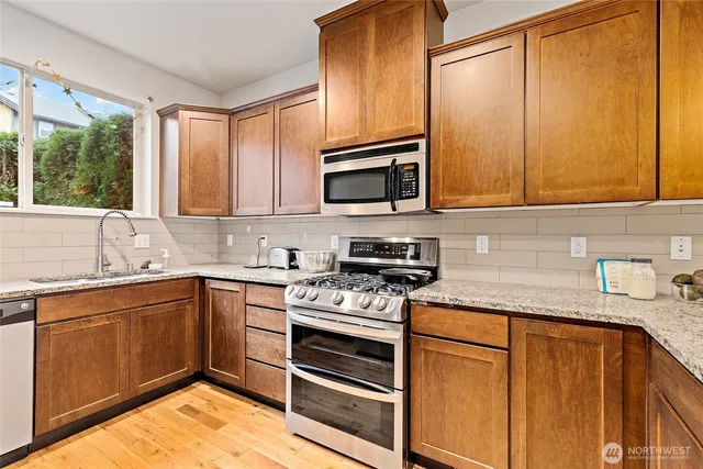 a kitchen with stainless steel appliances granite countertop wooden cabinets stove and a sink