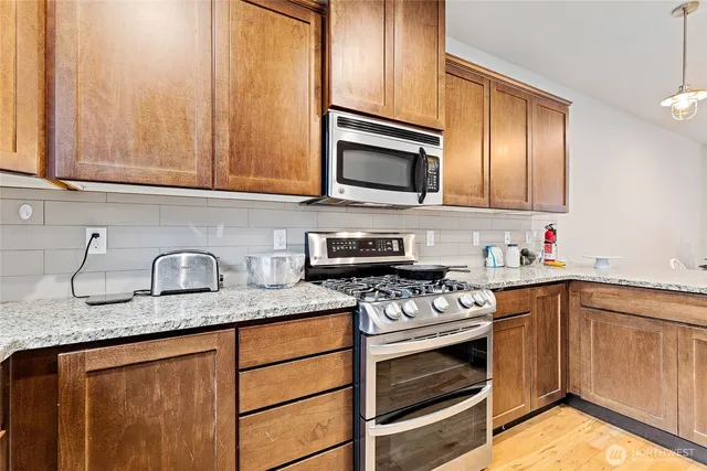a kitchen with granite countertop stainless steel appliances a stove sink and cabinets