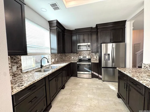 a kitchen with granite countertop a refrigerator and a stove top oven