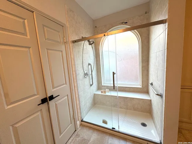 a bathroom with a glass shower door and a window