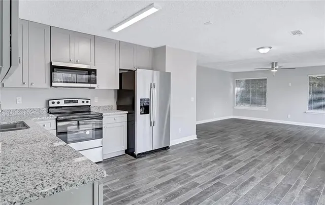 a kitchen with granite countertop a refrigerator and a stove top oven