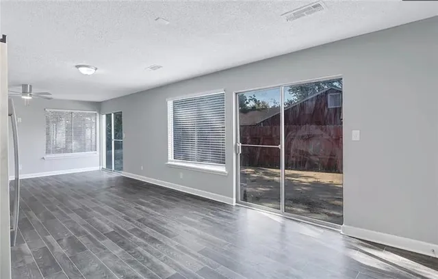 an empty room with wooden floor and windows