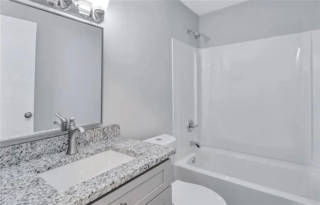 a bathroom with a granite countertop tub sink and mirror