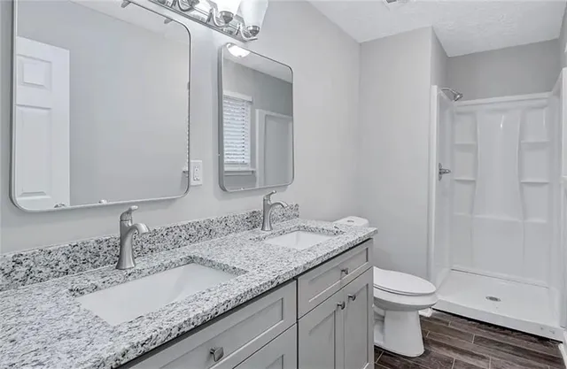 a bathroom with a granite countertop sink a toilet and a mirror