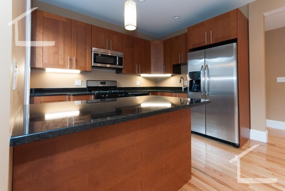 6 Lothian Road, Unit 3 Boston, MA 02135 - Photo 3 of 10 a kitchen with stainless steel appliances granite countertop a refrigerator a stove and a sink with wooden floor