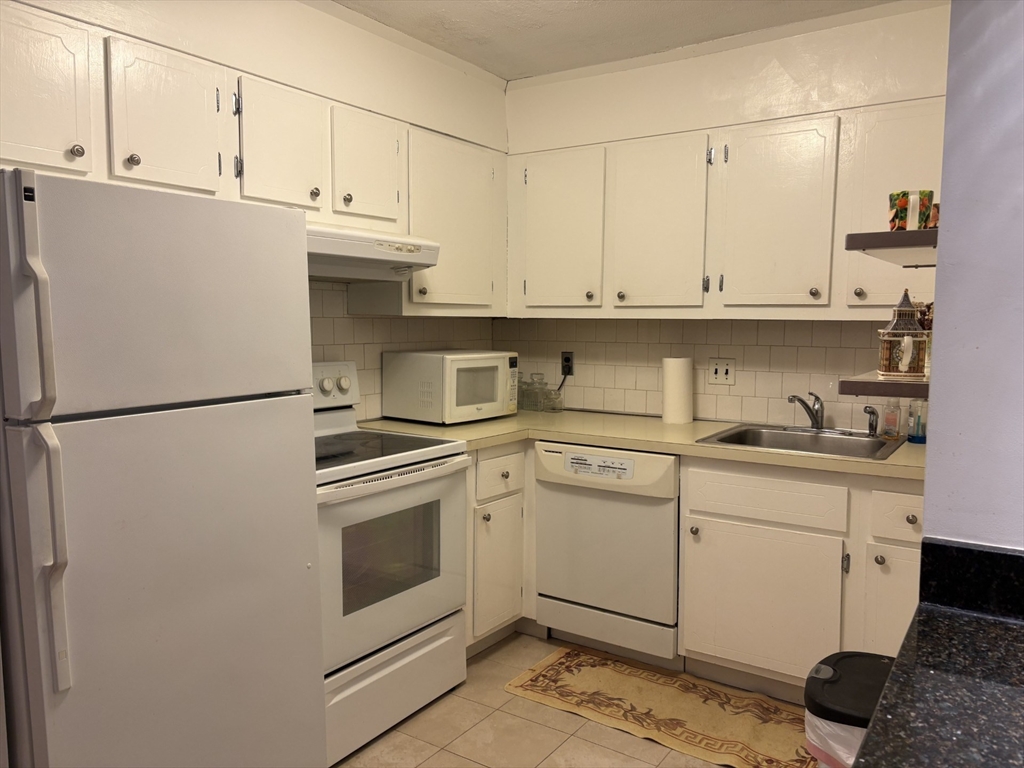 73 Walnut Street, Unit 6 Newton, MA 02460 - Photo 5 of 11 a kitchen with stainless steel appliances granite countertop a sink and a refrigerator