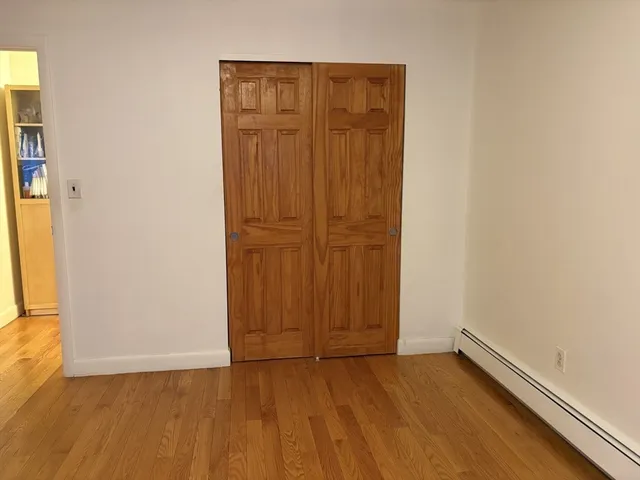 an empty room with wooden floor and closet area