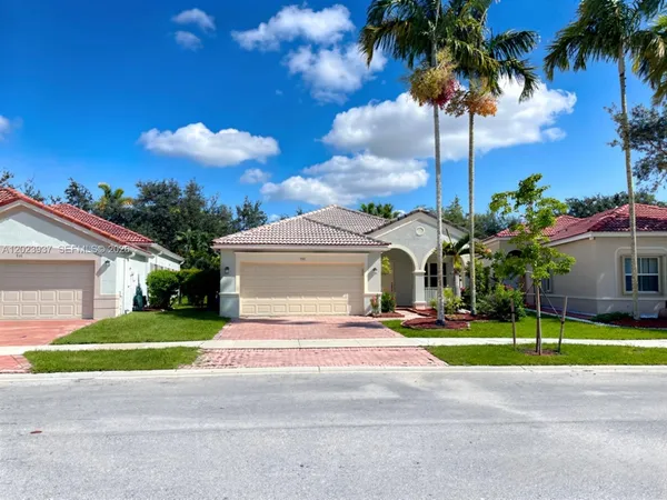 a front view of a house with a yard and palm trees