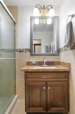 a bathroom with a granite countertop sink a mirror and a shower