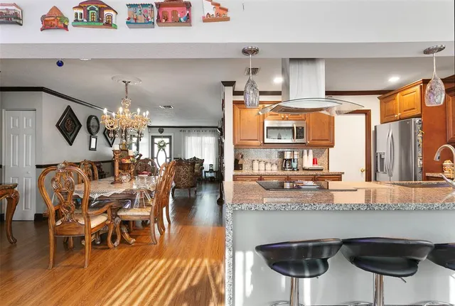 a kitchen with stainless steel appliances granite countertop a kitchen island and chairs in it
