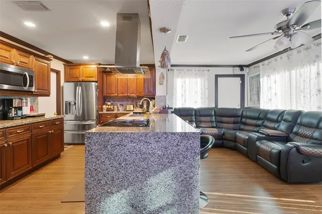 a large living room with stainless steel appliances granite countertop couches a fireplace and large kitchen view