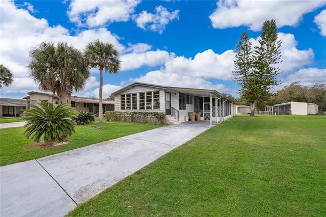 a view of house in front of a big yard with large trees