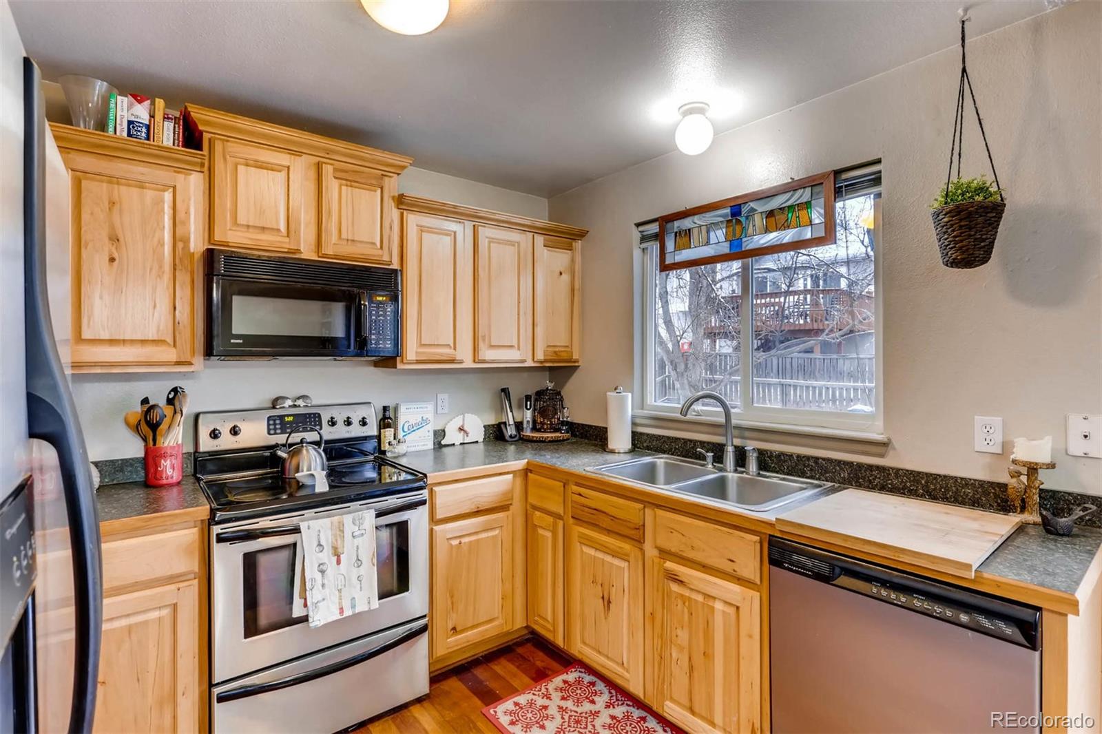 696 Myrtlewood Court Highlands Ranch, CO 80126 - Photo 5 of 12 a kitchen with stainless steel appliances granite countertop a sink stove microwave and cabinets