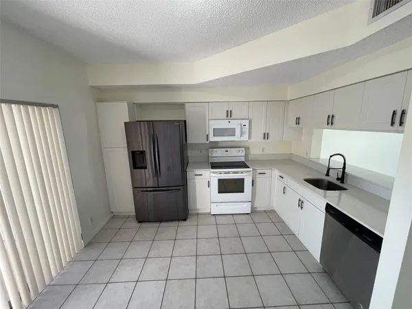 a kitchen with granite countertop a refrigerator and a sink