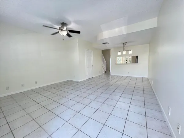 a view of an empty room and chandelier fan