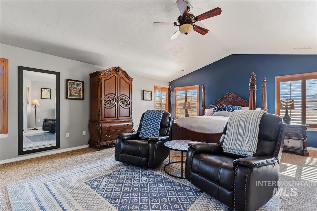 11660 Timber Butte Road Sweet, ID 83670 - Photo 19 of 49 Vaulted ceiling, ceiling fan with integrated lighting, wood-framed windows with plantation shutters, accent wall, and carpet flooring