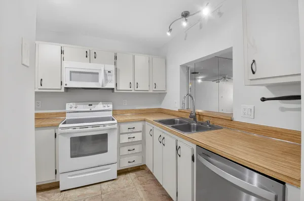 a kitchen with white cabinets and white appliances