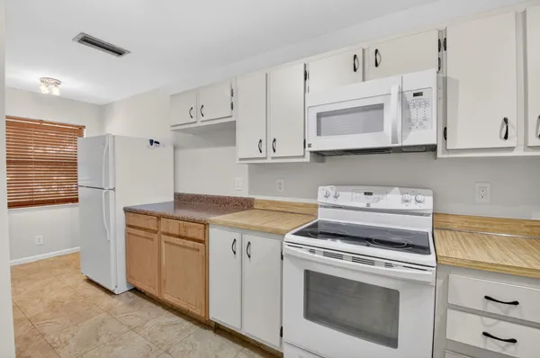 a kitchen with granite countertop white cabinets and white appliances
