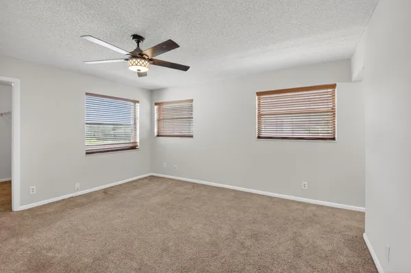 an empty room with windows and fan