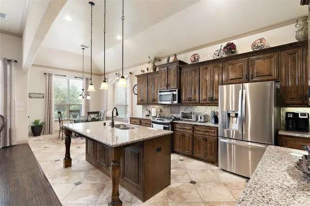 a kitchen with stainless steel appliances granite countertop a sink a stove and a refrigerator