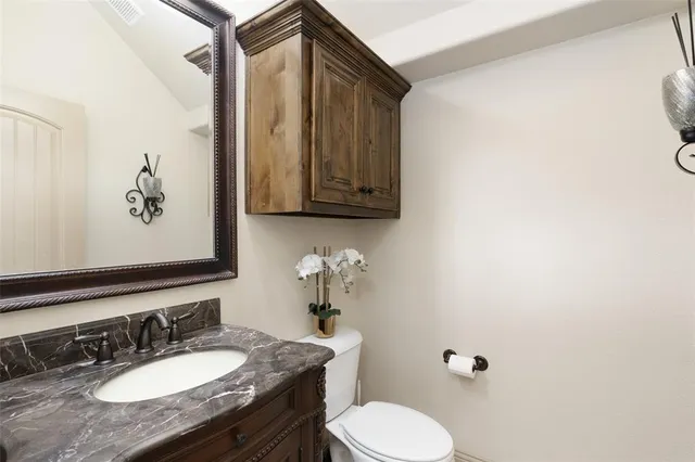 a bathroom with a granite countertop sink mirror and toilet