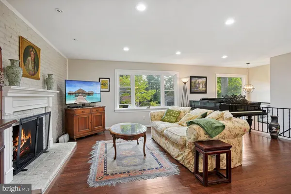 a living room with furniture a fireplace a flat screen tv and windows