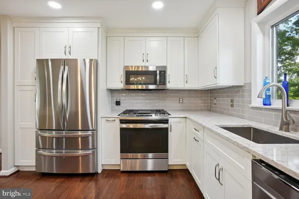 a kitchen with granite countertop a refrigerator stove and sink