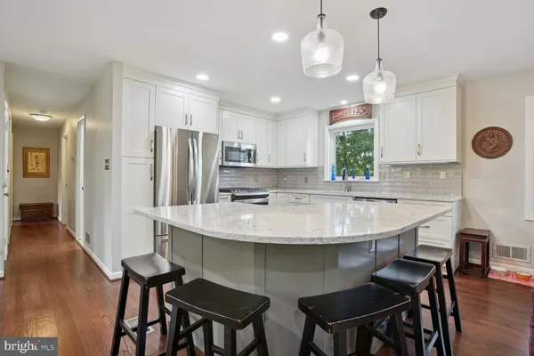 a kitchen with stainless steel appliances granite countertop a sink a stove a refrigerator and island with wooden floor