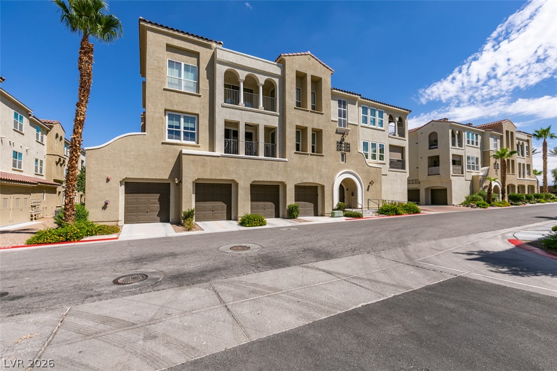 2555 Hampton Road, Unit 3203 Henderson, NV 89052 - Photo 2 of 43 Multi-level Mediterranean-inspired architecture showcases classic stucco finishes and integrated garages under a clear blue sky.