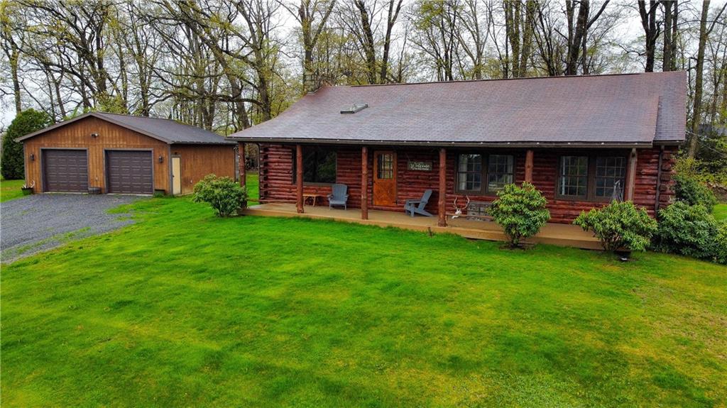 a view of a house with a yard plants and large tree