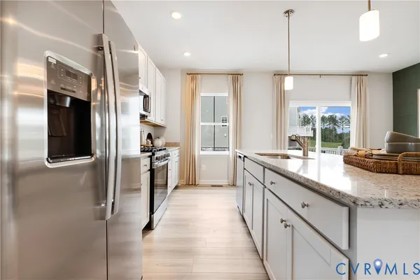 a large kitchen with a large counter top a sink a refrigerator and cabinets
