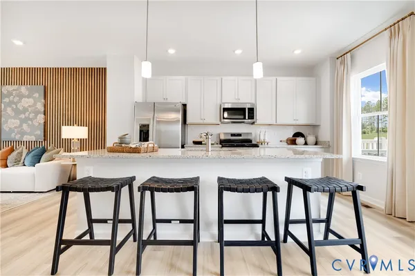 a kitchen with stainless steel appliances granite countertop a table chairs microwave and sink