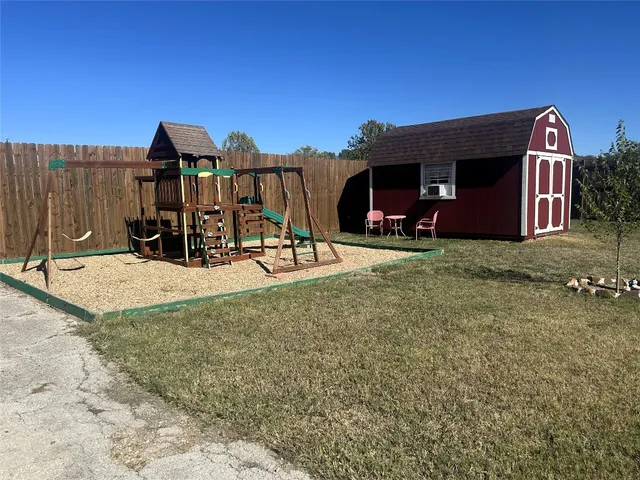 a view of a house with large trees and playing area