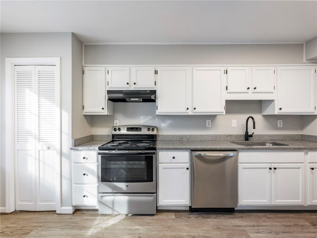 6500 Gaines Ferry Road, Unit A2 Flowery Branch, GA 30542 - Photo 3 of 42 a kitchen with stainless steel appliances granite countertop a sink and cabinets with wooden floors
