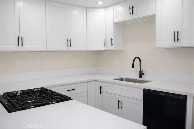 a kitchen with white cabinets a sink stove and dishwasher