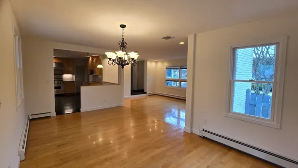 a view of a livingroom with a chandelier wooden floor and a chandelier