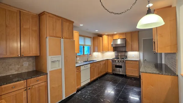 a kitchen with stainless steel appliances granite countertop a refrigerator and a sink