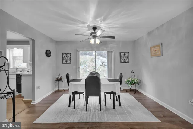 a dining room with furniture a floor to ceiling window and wooden floor