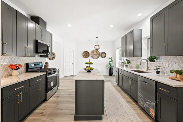 a kitchen with stainless steel appliances kitchen island granite countertop a sink stove and refrigerator