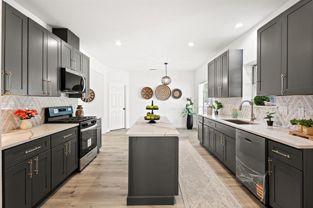 9502 Heartstone Lane Rowlett, TX 75087 - Photo 3 of 22 a kitchen with stainless steel appliances kitchen island granite countertop a sink stove and refrigerator