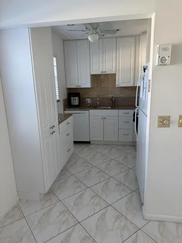 a kitchen with granite countertop a refrigerator and white cabinets