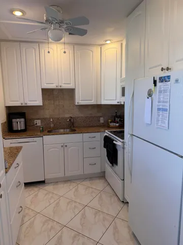 a kitchen with a refrigerator and white cabinets
