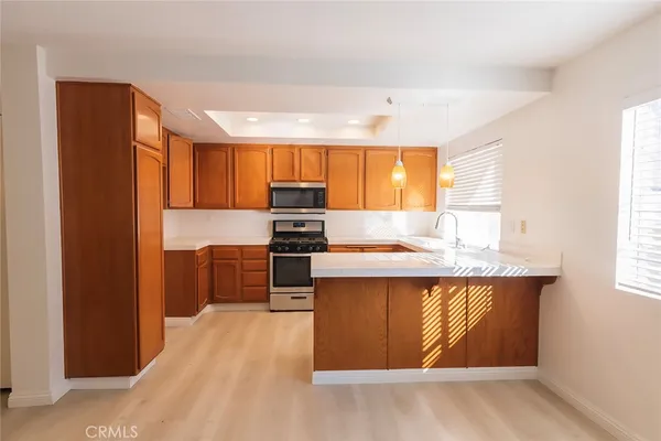 a kitchen with stainless steel appliances granite countertop a refrigerator a sink dishwasher a stove and white countertops with wooden floor