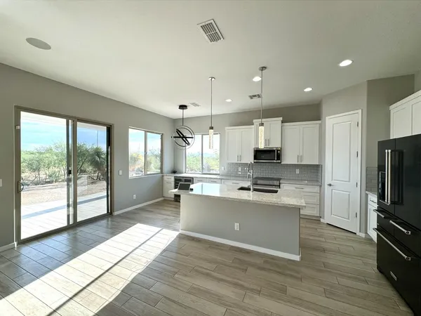 a kitchen with stainless steel appliances granite countertop a refrigerator a stove top oven a sink dishwasher and wooden floor