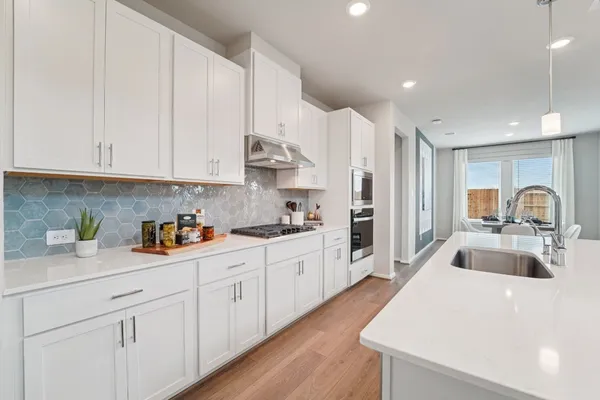 a kitchen with white cabinets and sink