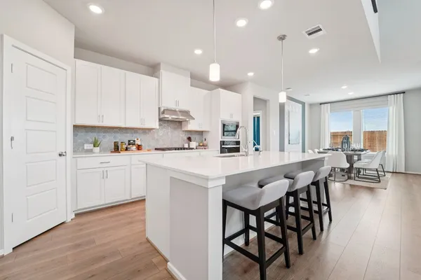 a kitchen with stainless steel appliances granite countertop a table chairs sink refrigerator and cabinets
