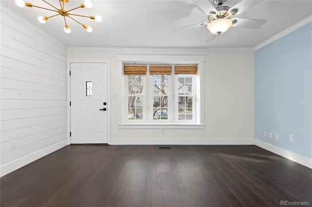 an empty room with wooden floor chandelier fan and windows