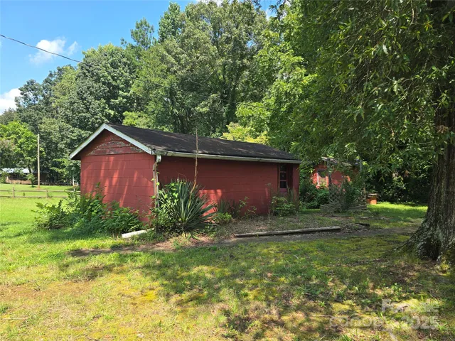 a house is sitting in middle of the green field